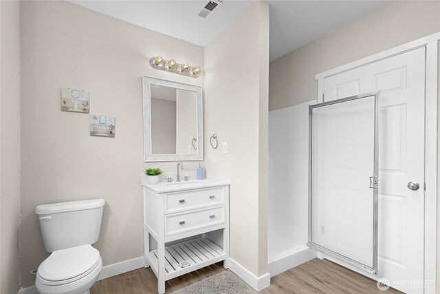 bathroom with baseboards, toilet, wood finished floors, and visible vents