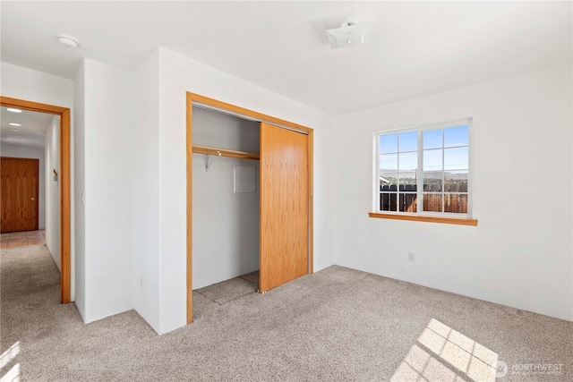 unfurnished bedroom with a closet and light colored carpet