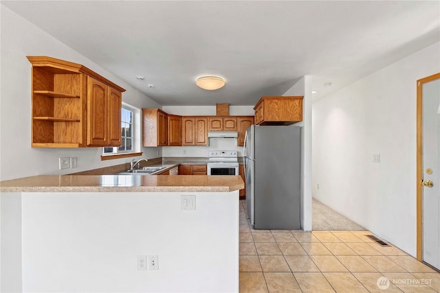kitchen with a sink, white range with electric cooktop, freestanding refrigerator, a peninsula, and under cabinet range hood