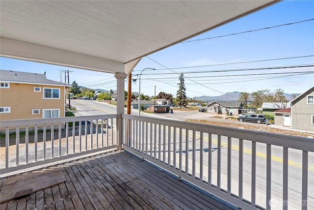deck featuring a residential view, a mountain view, and covered porch