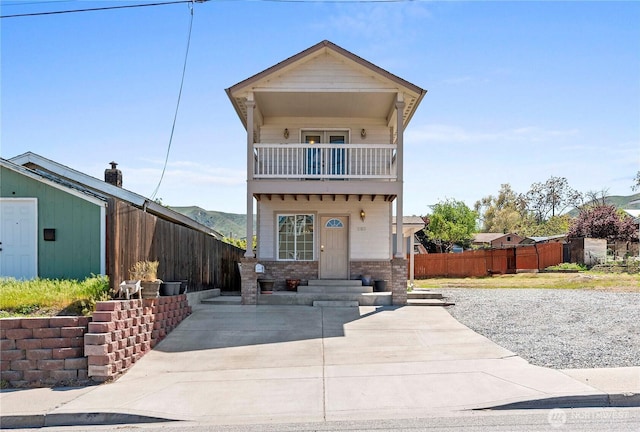 view of front of property with fence and a balcony
