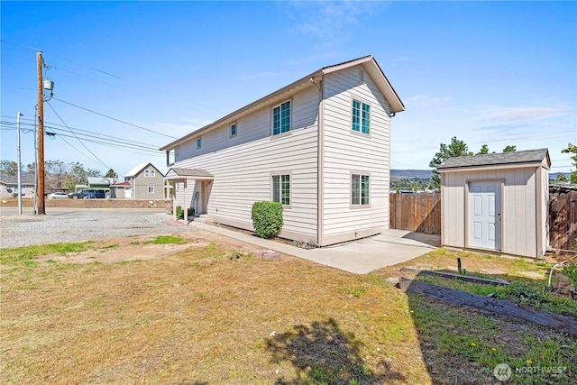 back of house featuring a storage shed, a lawn, fence, and an outbuilding
