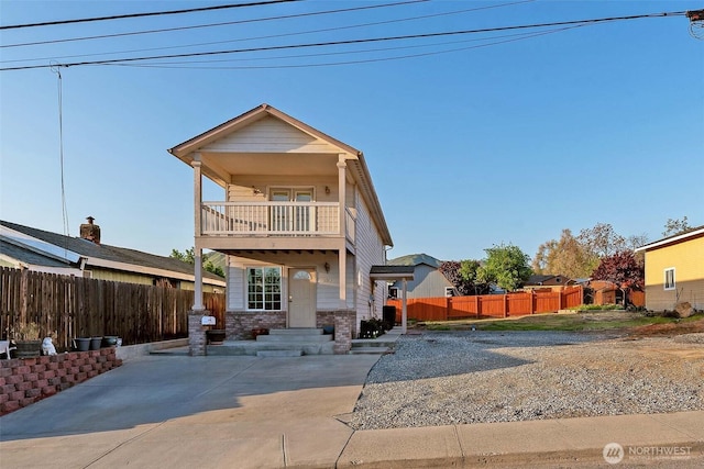 view of front of house with fence and a balcony