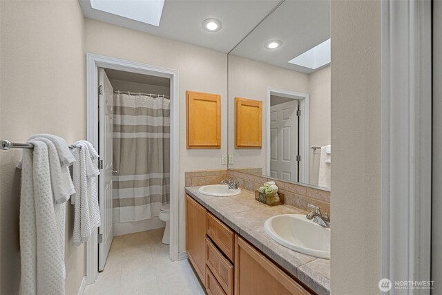 6211 116th Ave NE, Kirkland, WA 98033 - bathroom featuring a skylight, toilet, double vanity, curtained shower, and tile patterned flooring