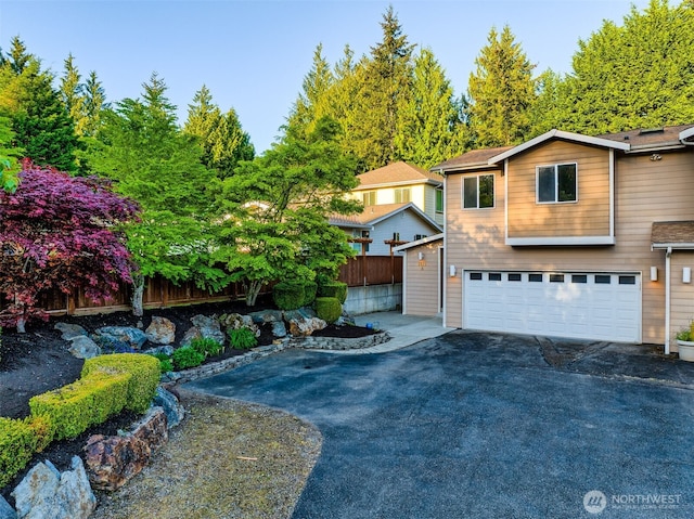 view of front of property with an attached garage, fence, and aphalt driveway