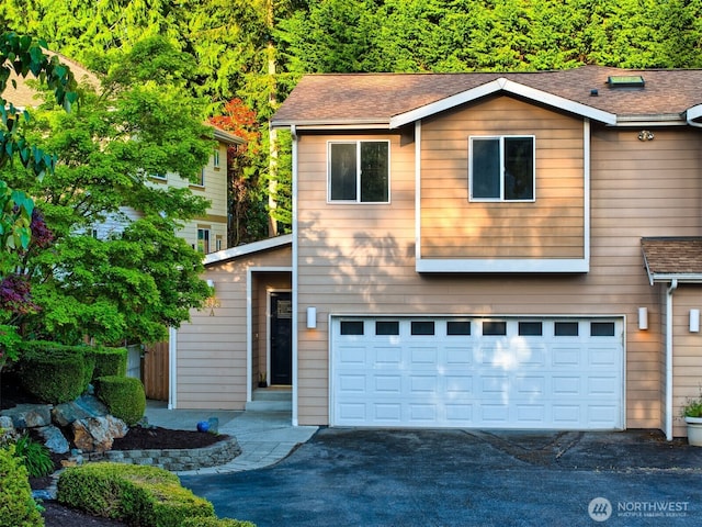 view of front of property with driveway, roof with shingles, and a garage