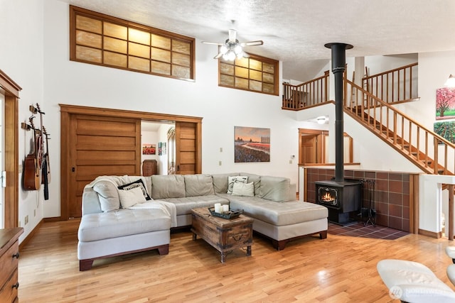 11451 O Ave, Anacortes, WA 98221 - living room with ceiling fan, a wood stove, light wood-style flooring, and a high ceiling