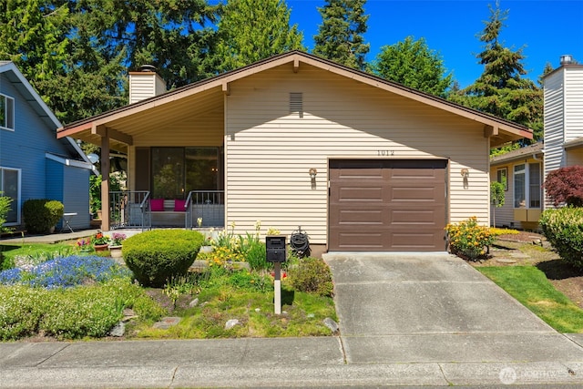 view of front of home with a chimney, driveway, covered porch, and a garage