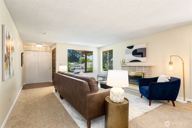 living area featuring a brick fireplace, light carpet, a textured ceiling, and baseboards