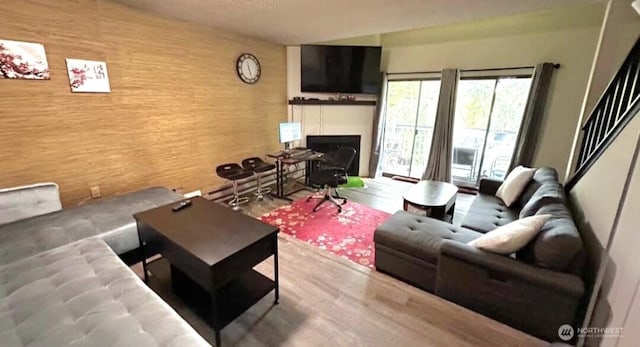 living room with wood walls, wood finished floors, and a fireplace