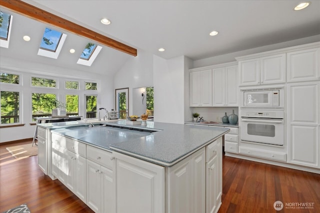 161 E Heron Cv, Shelton, WA 98584 - kitchen with a skylight, a center island with sink, beam ceiling, white appliances, and white cabinetry