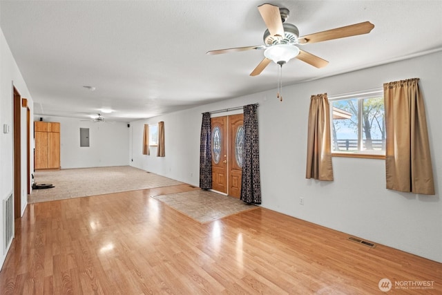 empty room with visible vents, ceiling fan, wood finished floors, and electric panel