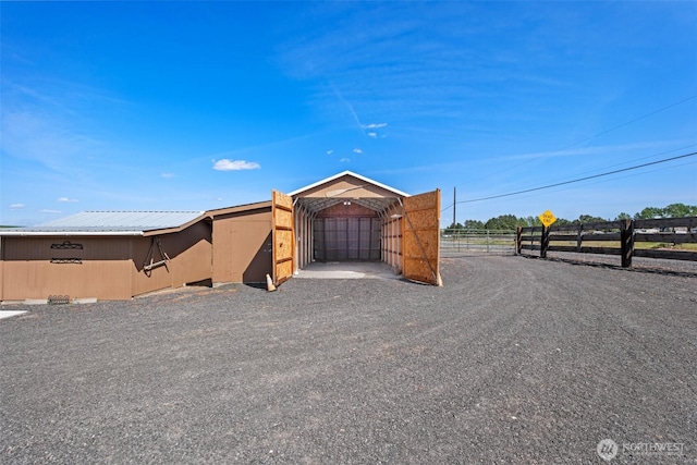 view of front of property featuring a detached carport, fence, and metal roof