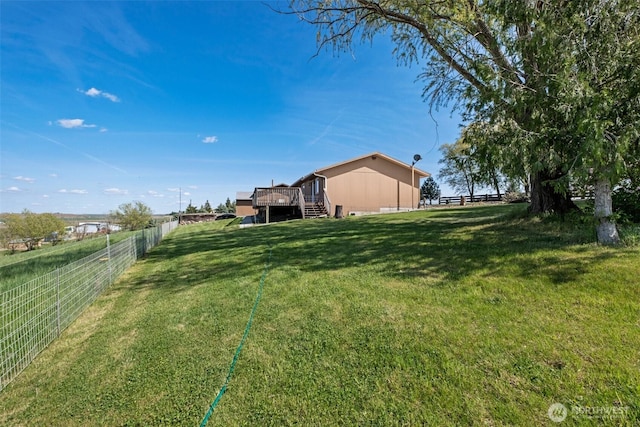 view of yard featuring fence, a wooden deck, and stairs