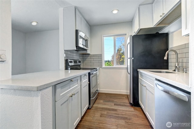 12429 NE 130th Ct Unit G201, Kirkland, WA 98034 - kitchen featuring a sink, dark wood finished floors, backsplash, baseboards, and appliances with stainless steel finishes