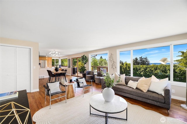 living area featuring baseboards, a notable chandelier, visible vents, and wood finished floors