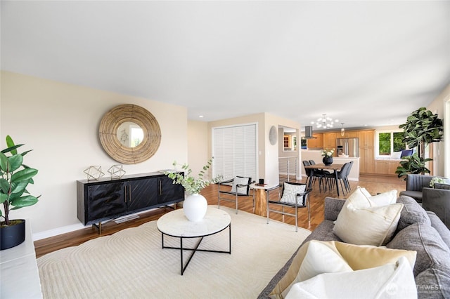 living room with an inviting chandelier, recessed lighting, light wood finished floors, and baseboards
