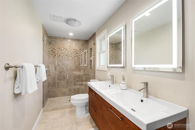 bathroom with toilet, visible vents, a tile shower, and a sink