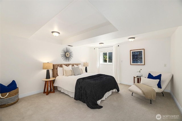 bedroom with a raised ceiling, baseboards, and light colored carpet