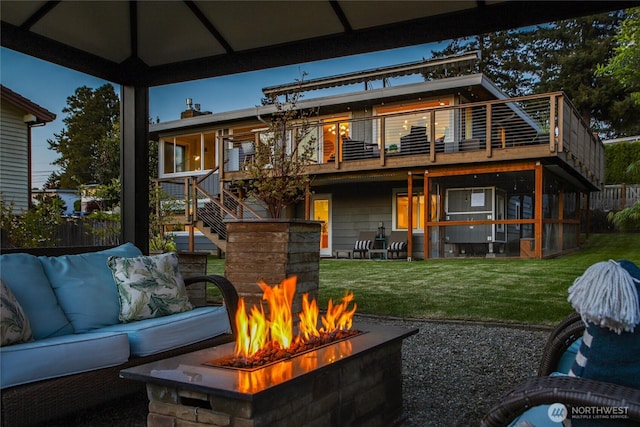 rear view of property with a lawn, a patio, stairs, and an outdoor living space with a fire pit