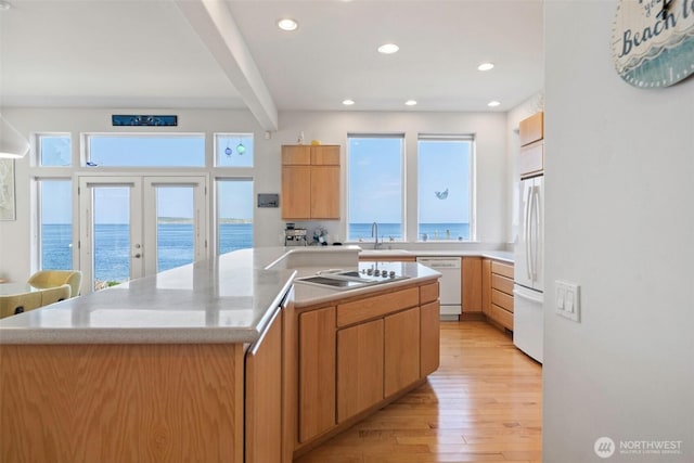kitchen featuring white appliances, a wealth of natural light, a sink, and a center island