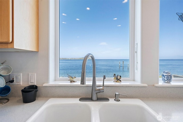 interior details featuring light countertops, a water view, and a sink