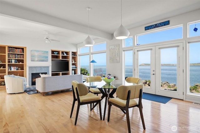 dining space featuring light wood-type flooring, beamed ceiling, visible vents, and a healthy amount of sunlight