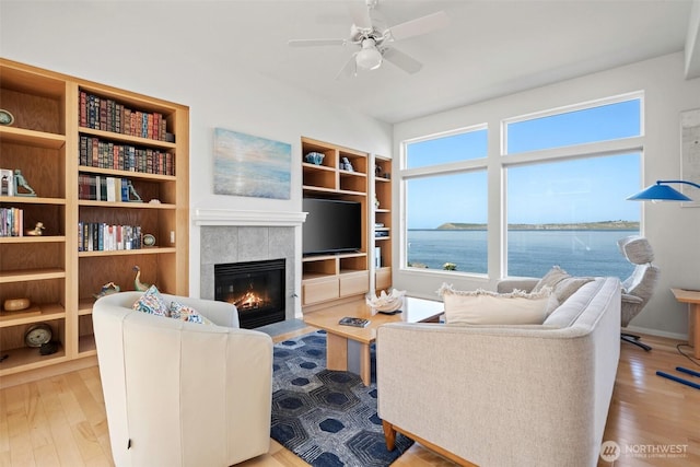 living room featuring plenty of natural light, a fireplace, a ceiling fan, and wood finished floors