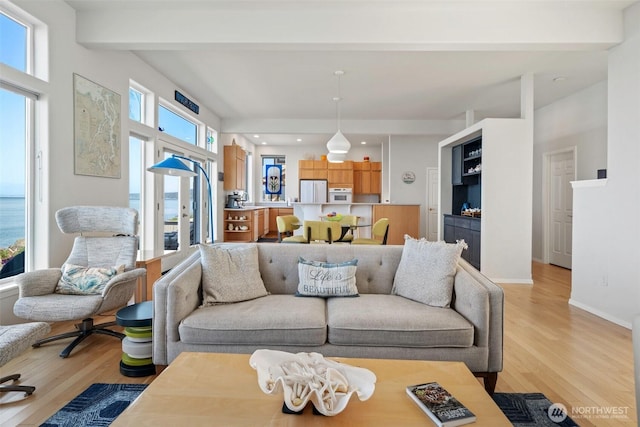 living room featuring recessed lighting, baseboards, beam ceiling, and light wood finished floors