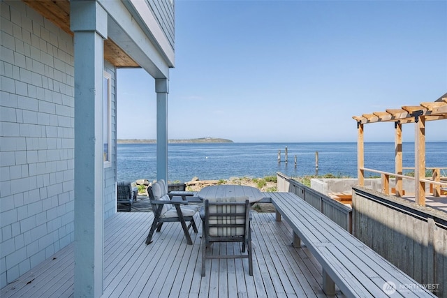 deck with outdoor dining area, a pergola, and a water view