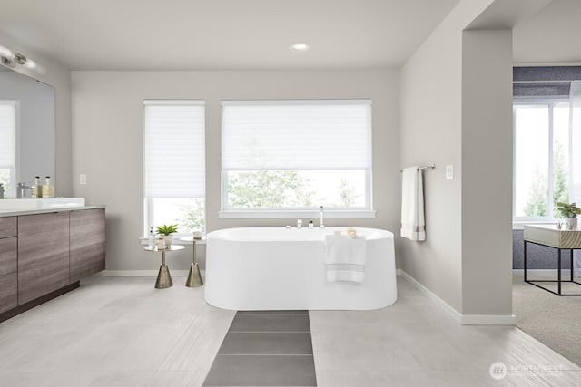 full bathroom with a freestanding bath, vanity, and plenty of natural light
