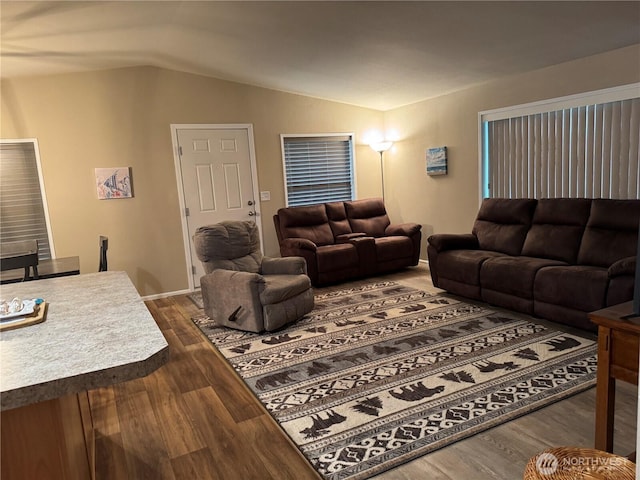 living area with baseboards, vaulted ceiling, and dark wood-style floors