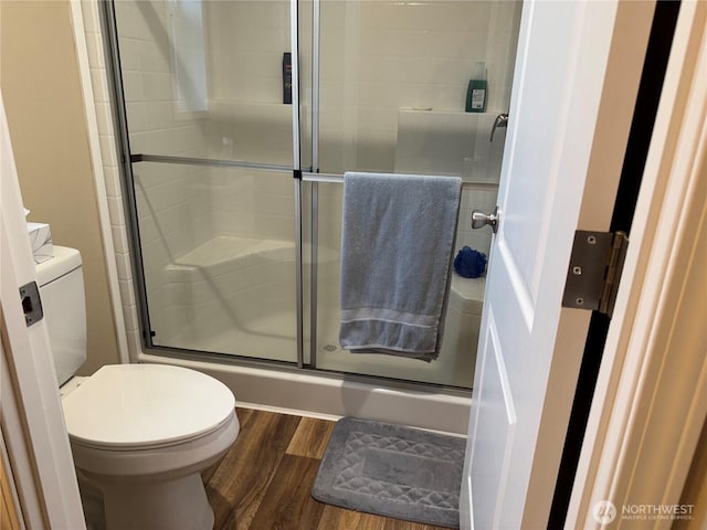 full bath with a shower stall, toilet, and wood finished floors