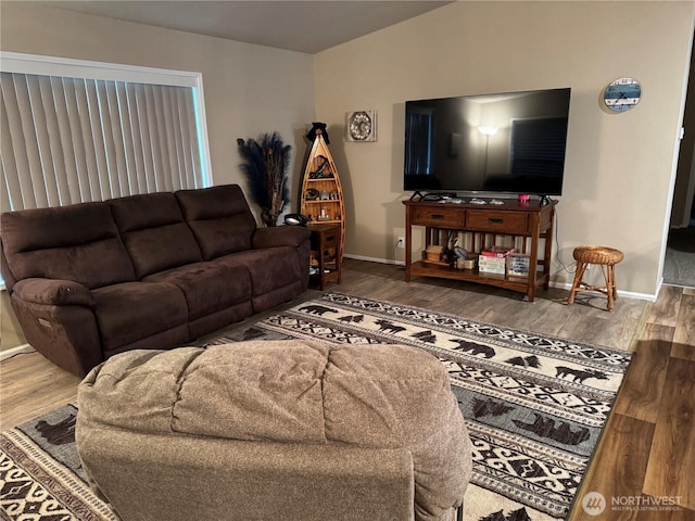 living room featuring baseboards, vaulted ceiling, and wood finished floors