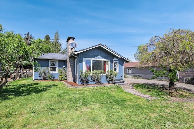 view of front of home with fence, a chimney, and a front yard