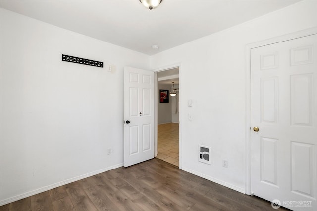 unfurnished bedroom featuring dark wood-style flooring and baseboards