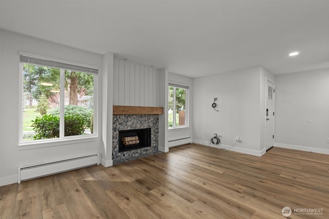 unfurnished living room featuring baseboard heating, a fireplace, baseboards, wood finished floors, and a baseboard radiator