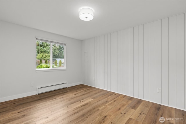 spare room featuring baseboards, baseboard heating, and light wood-type flooring