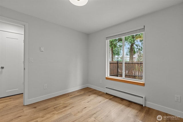 spare room with baseboards, a baseboard radiator, and light wood finished floors