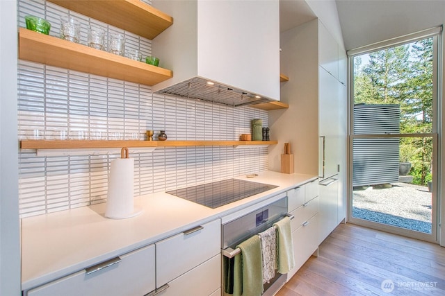 51 Lakshmi Rd, Orcas Island, WA 98245 - kitchen featuring open shelves, custom exhaust hood, wall oven, black electric stovetop, and decorative backsplash