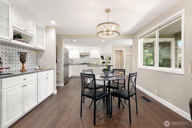dining room with an inviting chandelier, baseboards, visible vents, and dark wood-type flooring