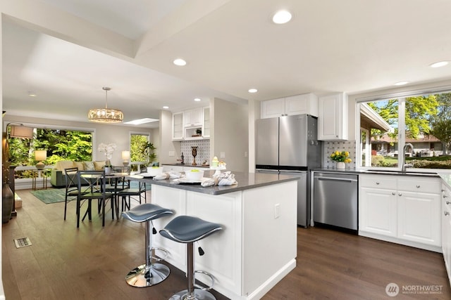 kitchen with a kitchen island, stainless steel appliances, dark wood-style floors, and tasteful backsplash