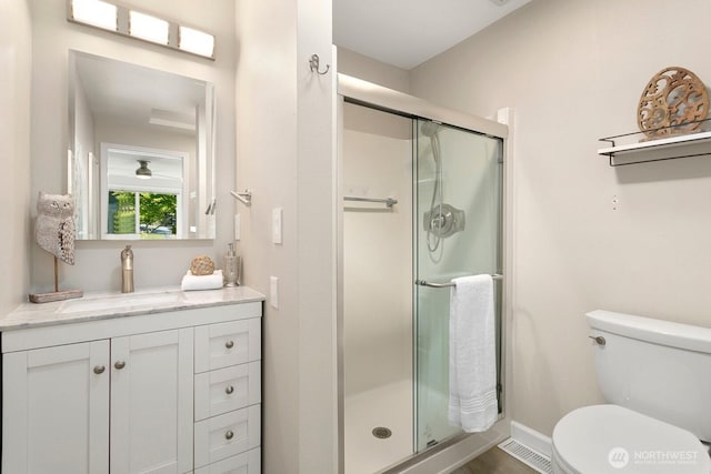 bathroom with vanity, baseboards, a stall shower, and toilet