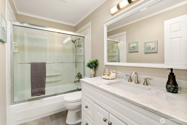 full bathroom featuring crown molding, vanity, toilet, wood finished floors, and bath / shower combo with glass door