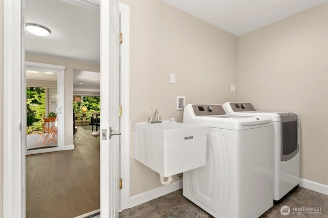 laundry area featuring separate washer and dryer, laundry area, a sink, and baseboards