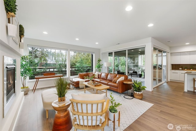 living area featuring light wood-type flooring, recessed lighting, and a premium fireplace