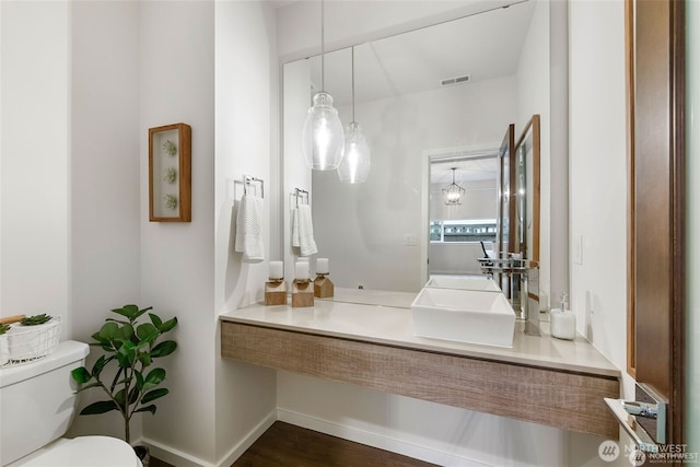 half bathroom featuring vanity, toilet, wood finished floors, and visible vents
