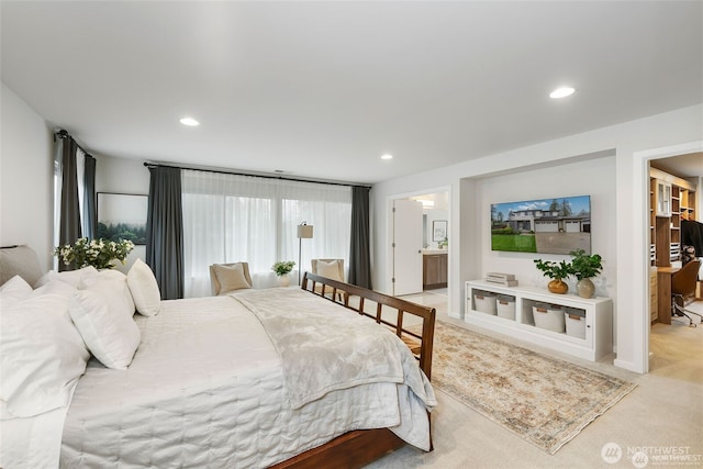 carpeted bedroom with ensuite bathroom and recessed lighting