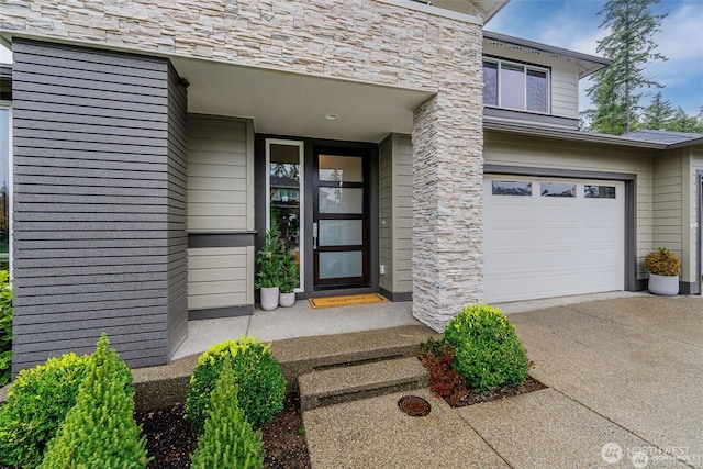 view of exterior entry featuring a garage, driveway, and stone siding