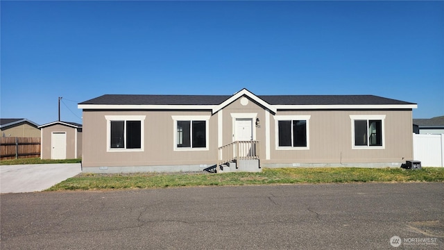 view of front facade featuring fence, roof with shingles, and crawl space